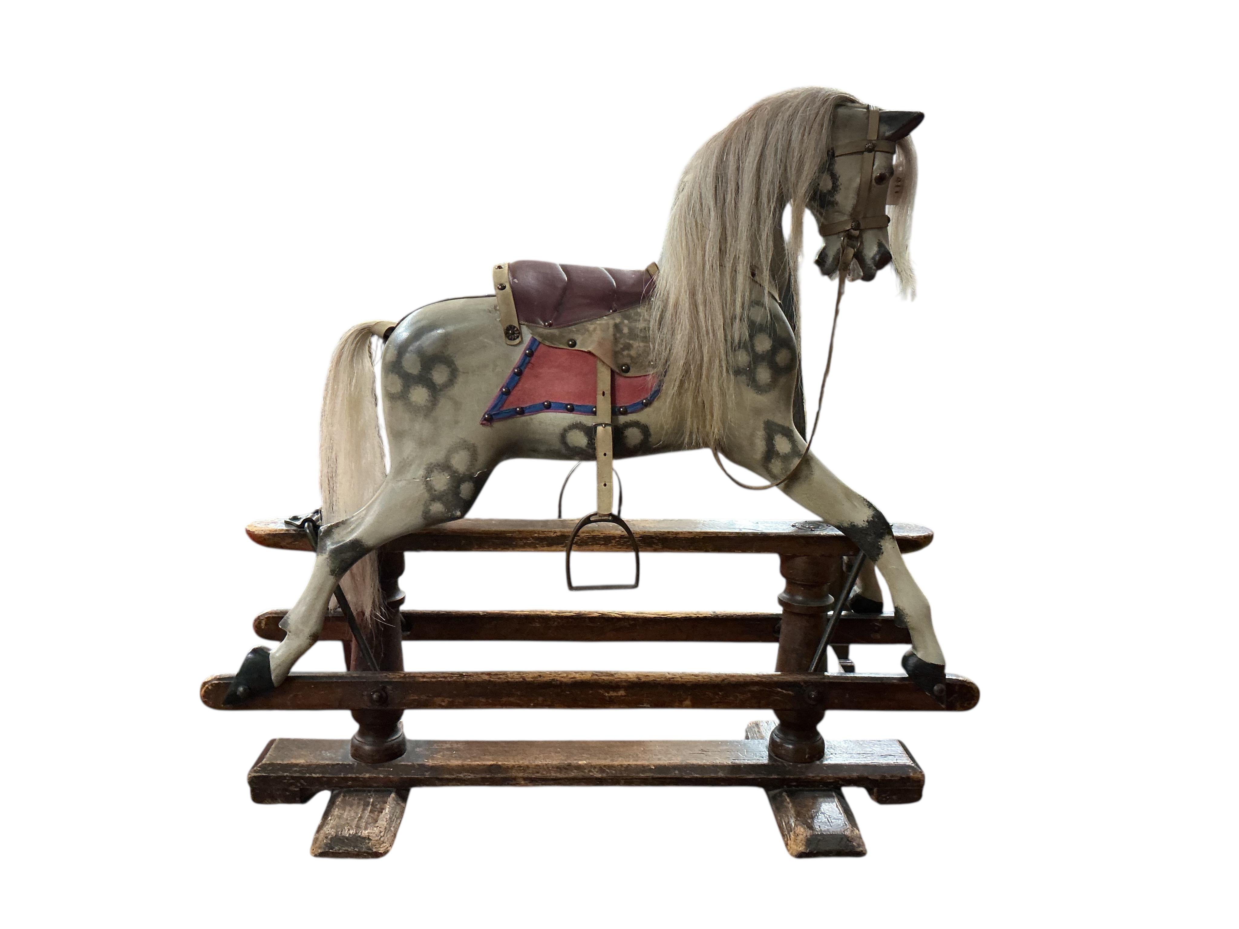 An Ayres type dappled grey painted rocking horse, pine base and runners with good patination and applied brass roundels to both the base and the horse celebrating Queen Victoria‘s Golden Jubilee in 1887, the horse has be